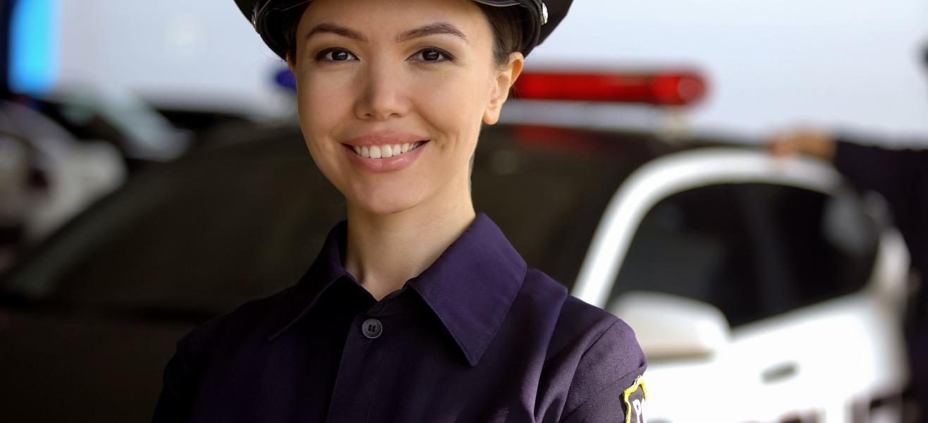 smiling police officer in front of her patrol car- stock image