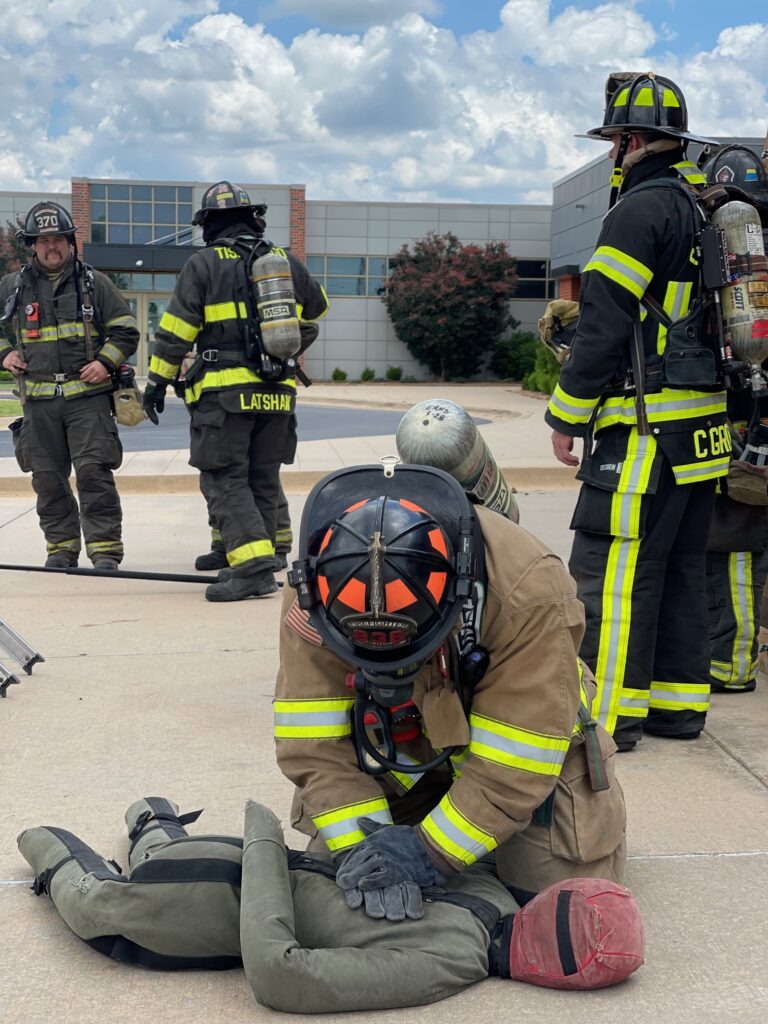 firefighter simulates CPR on fabric body.