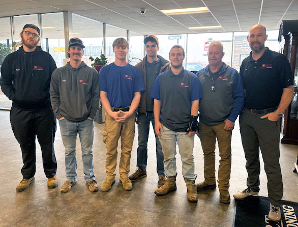 Seven HVAC technicians stand beside the co-owner of DeHart Air Conditioning at the company's Chickasha location. A total of 15 technicians who were trained at CV Tech comprise nearly 70 percent of DeHart's 25-person service team.